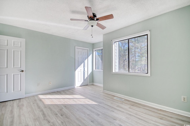 empty room featuring ceiling fan, light hardwood / wood-style floors, and a textured ceiling