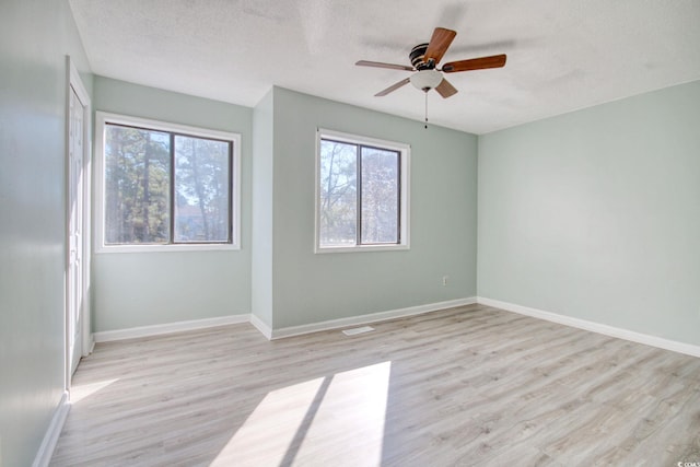 empty room with a textured ceiling, light wood-type flooring, and ceiling fan