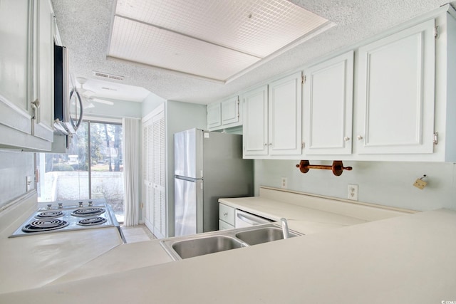 kitchen featuring stainless steel appliances, white cabinetry, sink, and a textured ceiling