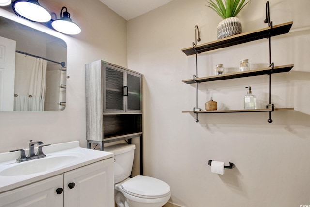 bathroom featuring toilet, vanity, and a shower with curtain