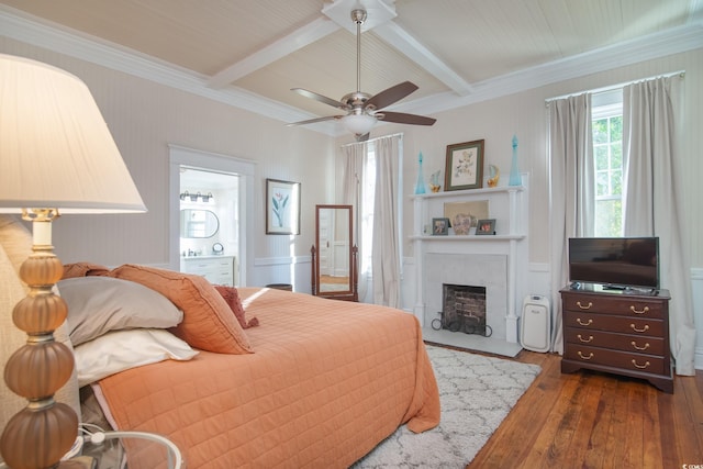 bedroom with ceiling fan, ensuite bath, dark hardwood / wood-style flooring, a fireplace, and beam ceiling