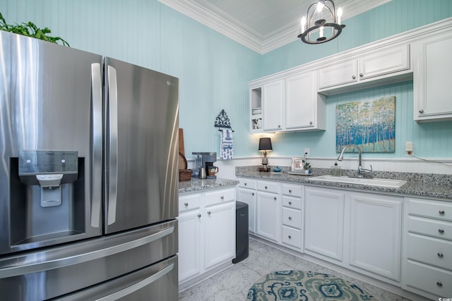 kitchen with stainless steel refrigerator with ice dispenser, white cabinetry, light stone counters, and sink