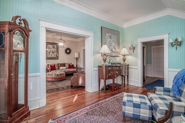 living area featuring an inviting chandelier, crown molding, and hardwood / wood-style flooring