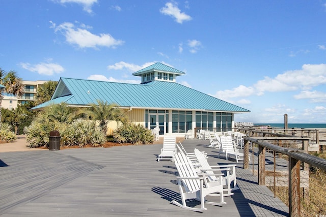 view of patio featuring a deck with water view and a sunroom