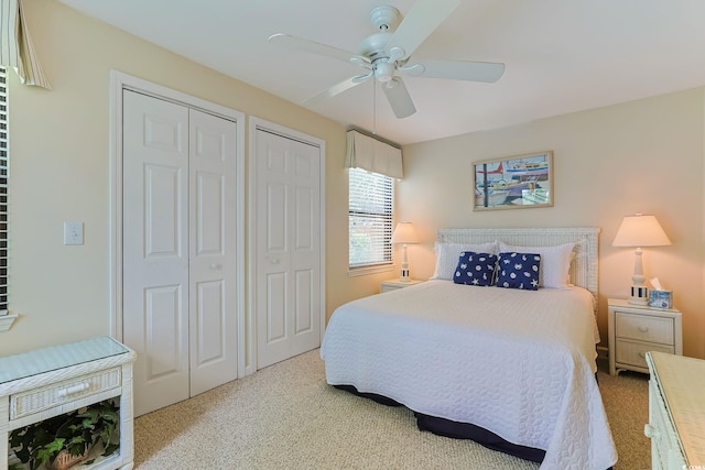 carpeted bedroom with two closets and ceiling fan