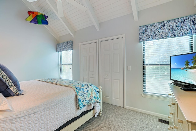 carpeted bedroom with lofted ceiling with beams, wood ceiling, and multiple closets