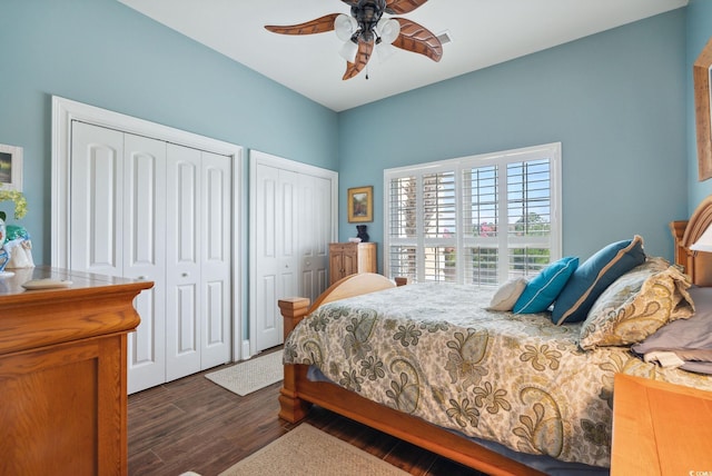 bedroom featuring dark wood-style floors, two closets, and a ceiling fan