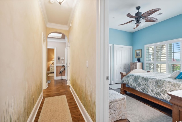 bedroom with visible vents, baseboards, ornamental molding, wood finished floors, and arched walkways