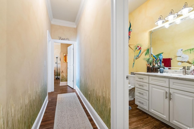 hallway with a sink, baseboards, dark wood-style floors, and ornamental molding