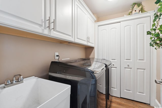 clothes washing area with washer and dryer, cabinet space, light wood-style floors, and a sink