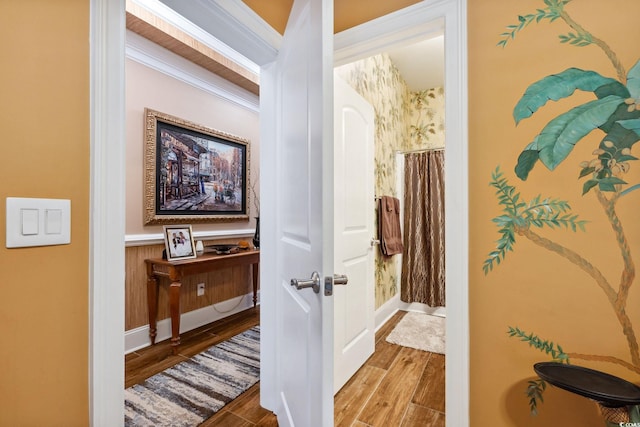 hall with wood finished floors, baseboards, and ornamental molding