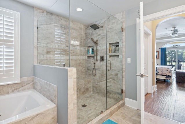 bathroom with a shower stall, baseboards, ceiling fan, a garden tub, and ensuite bath