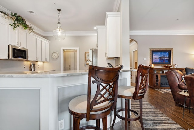 kitchen with stainless steel microwave, visible vents, crown molding, white cabinetry, and dark wood-style flooring