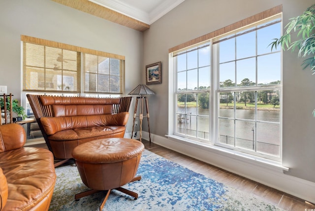 interior space featuring wood finished floors, baseboards, a water view, and ornamental molding