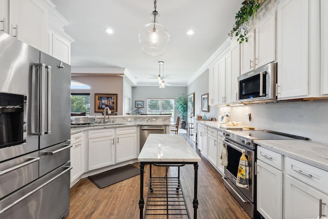 kitchen with crown molding, appliances with stainless steel finishes, a peninsula, white cabinets, and a sink