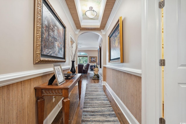 hall with a wainscoted wall, dark wood-type flooring, and ornamental molding