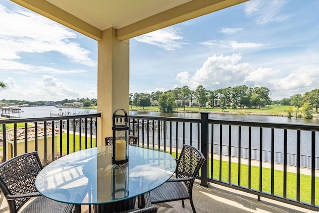 balcony with outdoor dining space and a water view