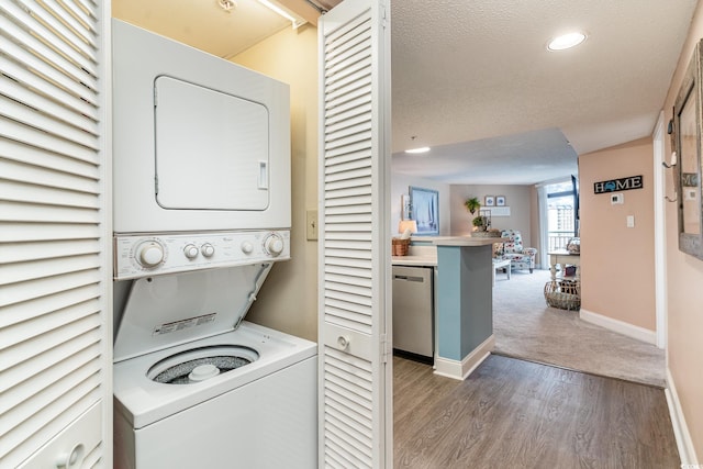 washroom featuring stacked washer and dryer, a textured ceiling, and hardwood / wood-style flooring