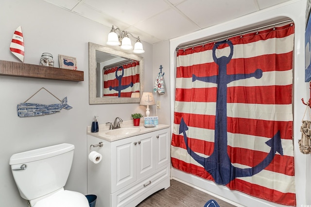 bathroom featuring walk in shower, wood-type flooring, toilet, a paneled ceiling, and vanity