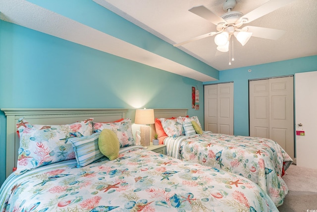 carpeted bedroom with multiple closets, ceiling fan, and a textured ceiling