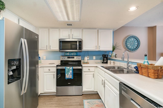 kitchen featuring white cabinets, light wood-type flooring, stainless steel appliances, and sink