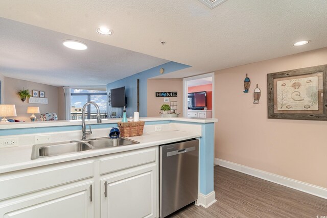 kitchen featuring stainless steel dishwasher, a textured ceiling, sink, white cabinets, and hardwood / wood-style floors