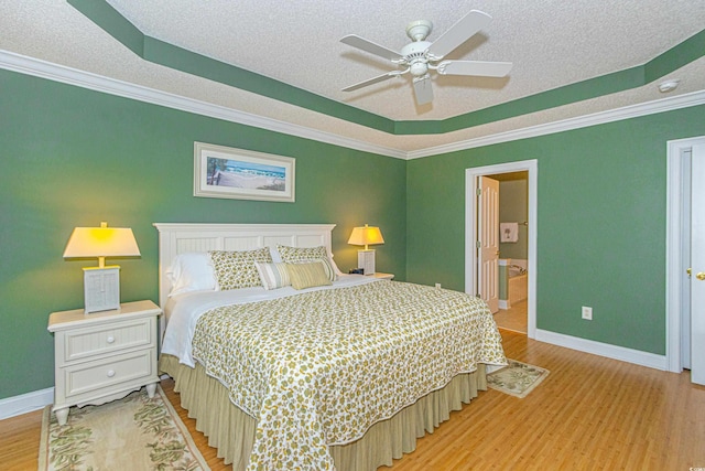 bedroom featuring a textured ceiling, ensuite bath, light hardwood / wood-style flooring, and ceiling fan