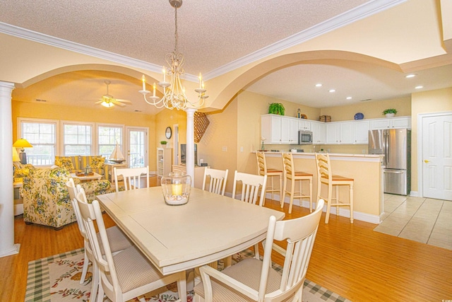 dining space featuring ceiling fan with notable chandelier, decorative columns, crown molding, and light hardwood / wood-style floors