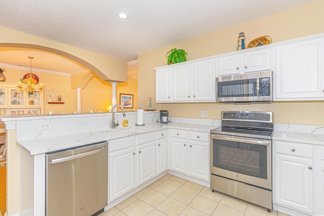 kitchen with kitchen peninsula, light tile patterned floors, stainless steel appliances, and white cabinets