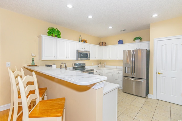 kitchen with kitchen peninsula, a breakfast bar, stainless steel appliances, and white cabinetry