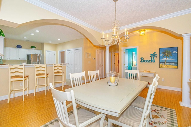 dining area with a textured ceiling, a notable chandelier, crown molding, and light hardwood / wood-style flooring