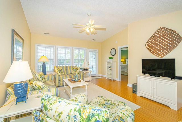 living room featuring a textured ceiling, ceiling fan, light hardwood / wood-style flooring, and lofted ceiling