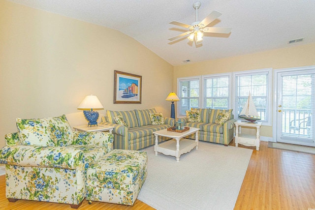 living room with a textured ceiling, ceiling fan, wood-type flooring, and vaulted ceiling