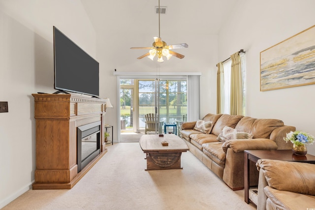 living room featuring ceiling fan, a towering ceiling, and light carpet