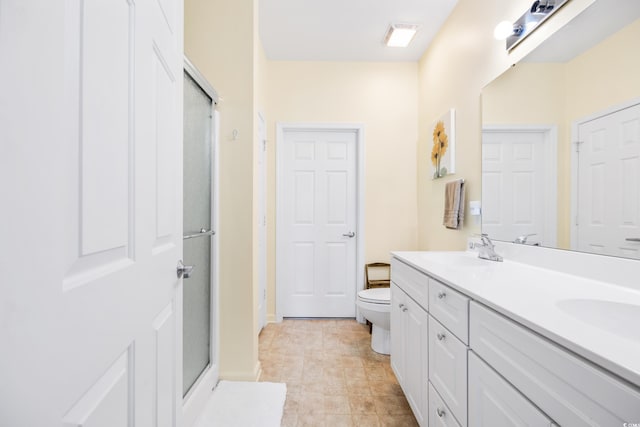 bathroom featuring vanity, toilet, and a shower with door