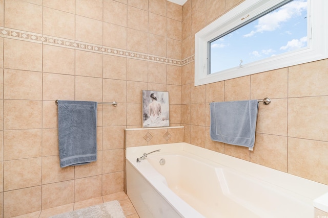 bathroom featuring a washtub and tile walls