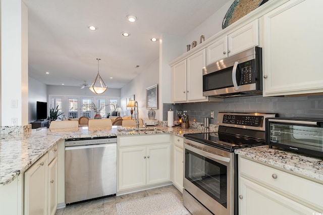 kitchen with tasteful backsplash, sink, light stone counters, kitchen peninsula, and stainless steel appliances