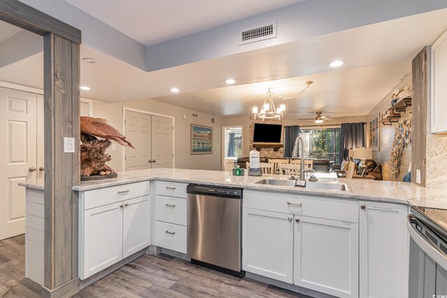 kitchen with kitchen peninsula, dishwasher, white cabinets, and sink