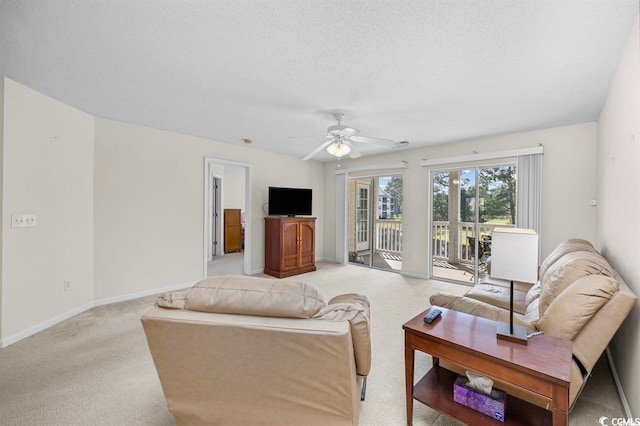 living area featuring light carpet, ceiling fan, a textured ceiling, and baseboards