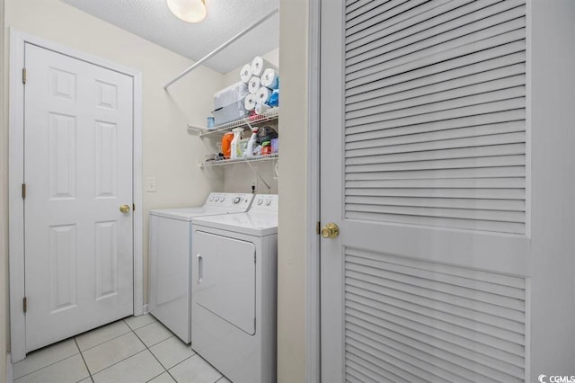 washroom with light tile patterned floors, laundry area, a textured ceiling, and independent washer and dryer