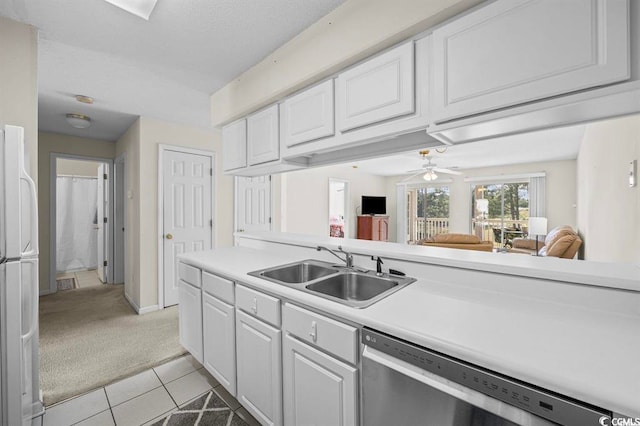 kitchen featuring light tile patterned flooring, light colored carpet, a sink, white cabinets, and stainless steel dishwasher