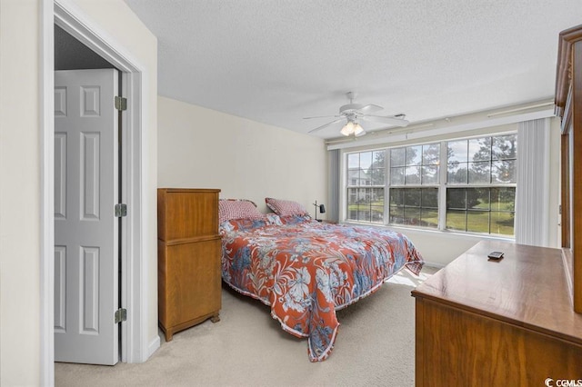 bedroom with a ceiling fan, light colored carpet, and a textured ceiling