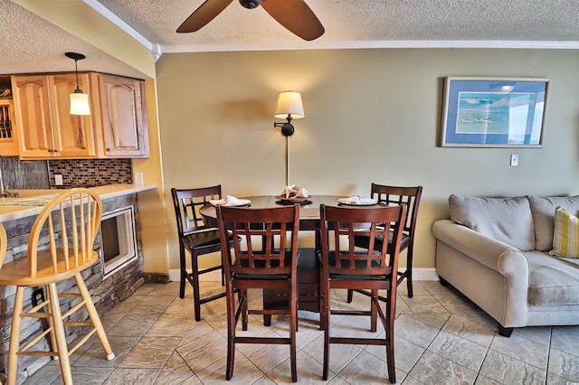 dining room featuring ceiling fan, a textured ceiling, and ornamental molding