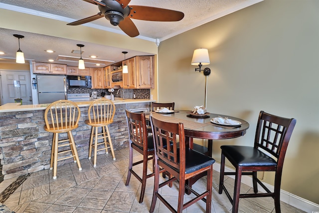 dining room with a textured ceiling, ceiling fan, crown molding, and sink