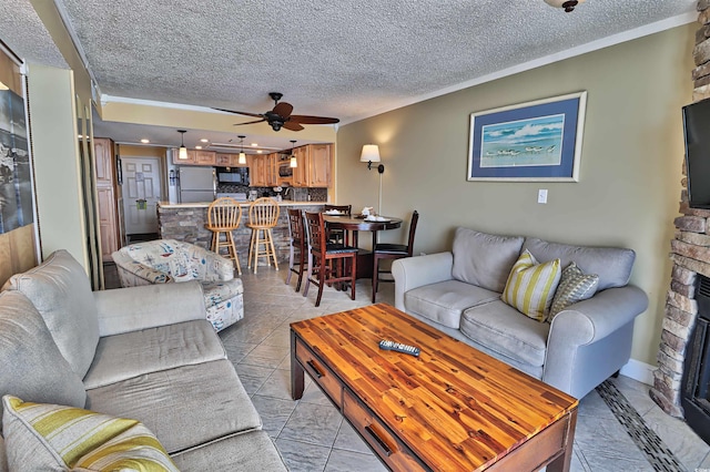 tiled living room featuring ceiling fan, a fireplace, and a textured ceiling