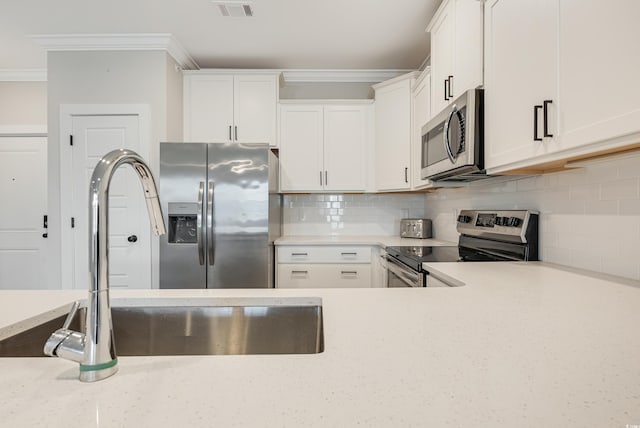 kitchen featuring tasteful backsplash, white cabinets, and appliances with stainless steel finishes