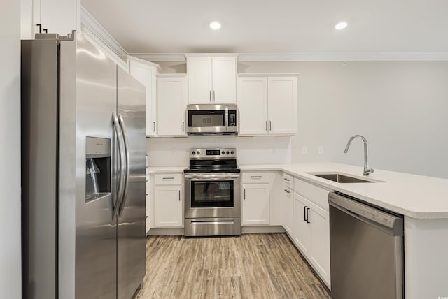 kitchen with kitchen peninsula, appliances with stainless steel finishes, crown molding, sink, and white cabinets