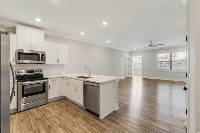 kitchen with kitchen peninsula, sink, white cabinets, and stainless steel appliances