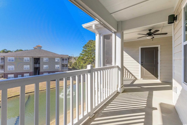 balcony with ceiling fan and a water view