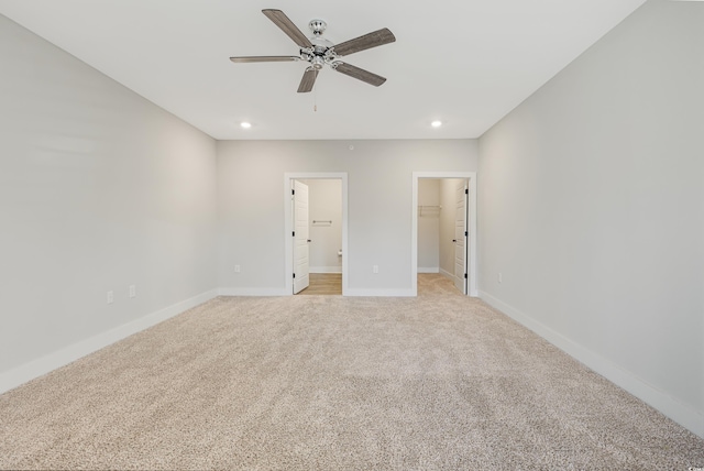 unfurnished bedroom featuring ceiling fan, light colored carpet, a spacious closet, and a closet